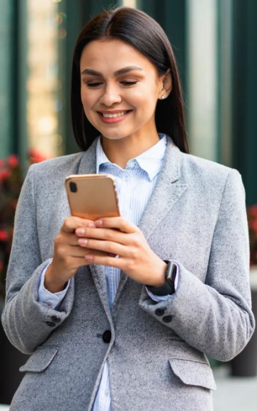 smiley-businesswoman-with-smartphone-outdoors